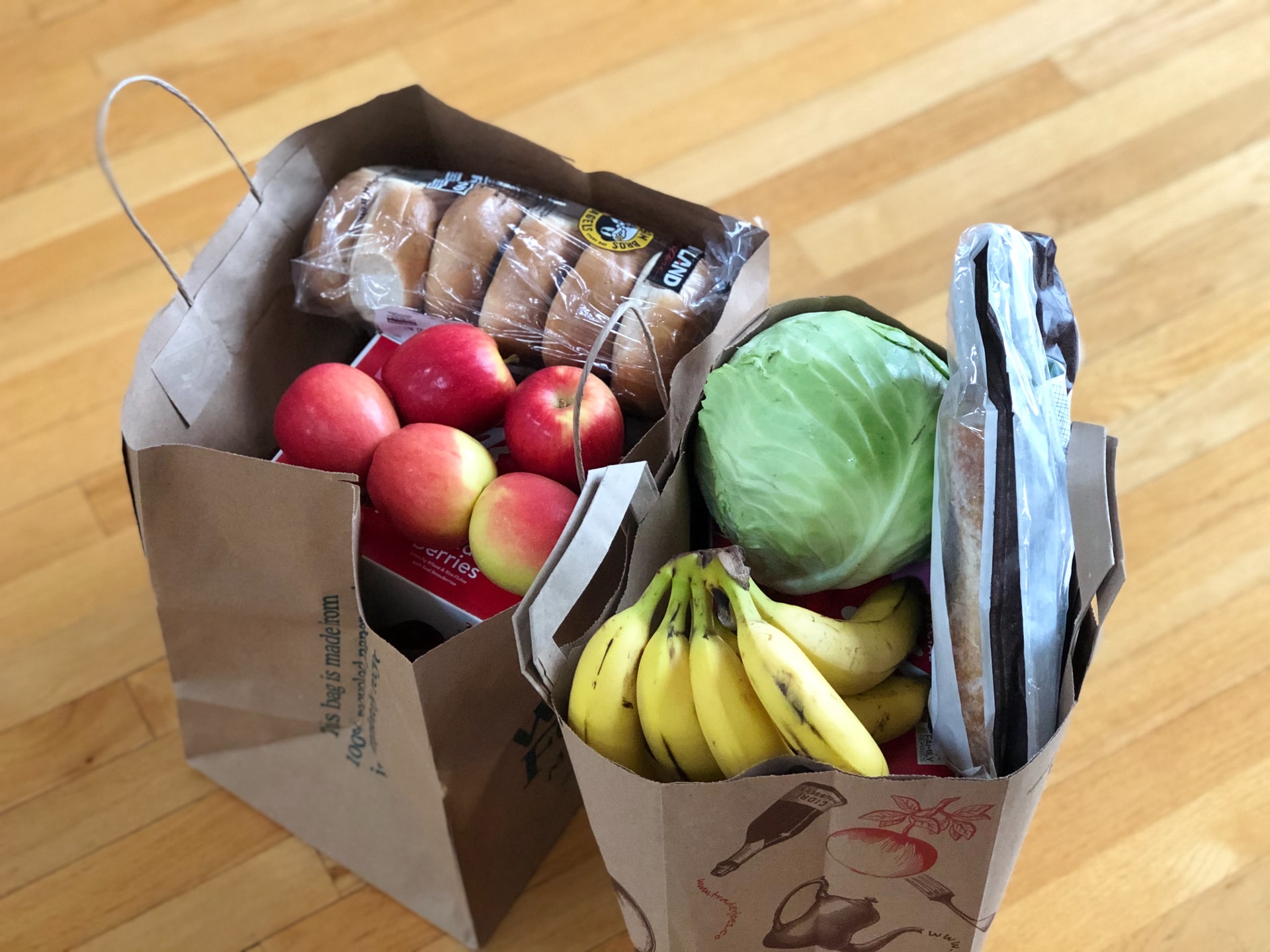 [Foto de sacos de compras cheios de fruta, legumes e pão]